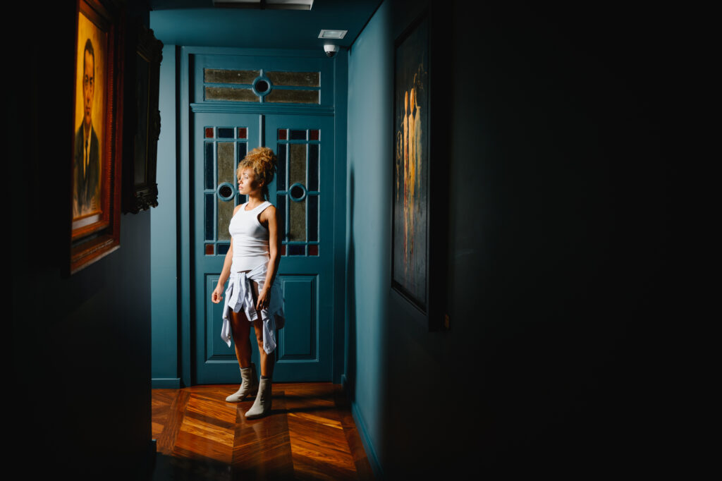 AQA light beige ankle boots for women, showcased in a dramatic gallery hallway with artistic lighting - Spring/Summer 26 Collection.