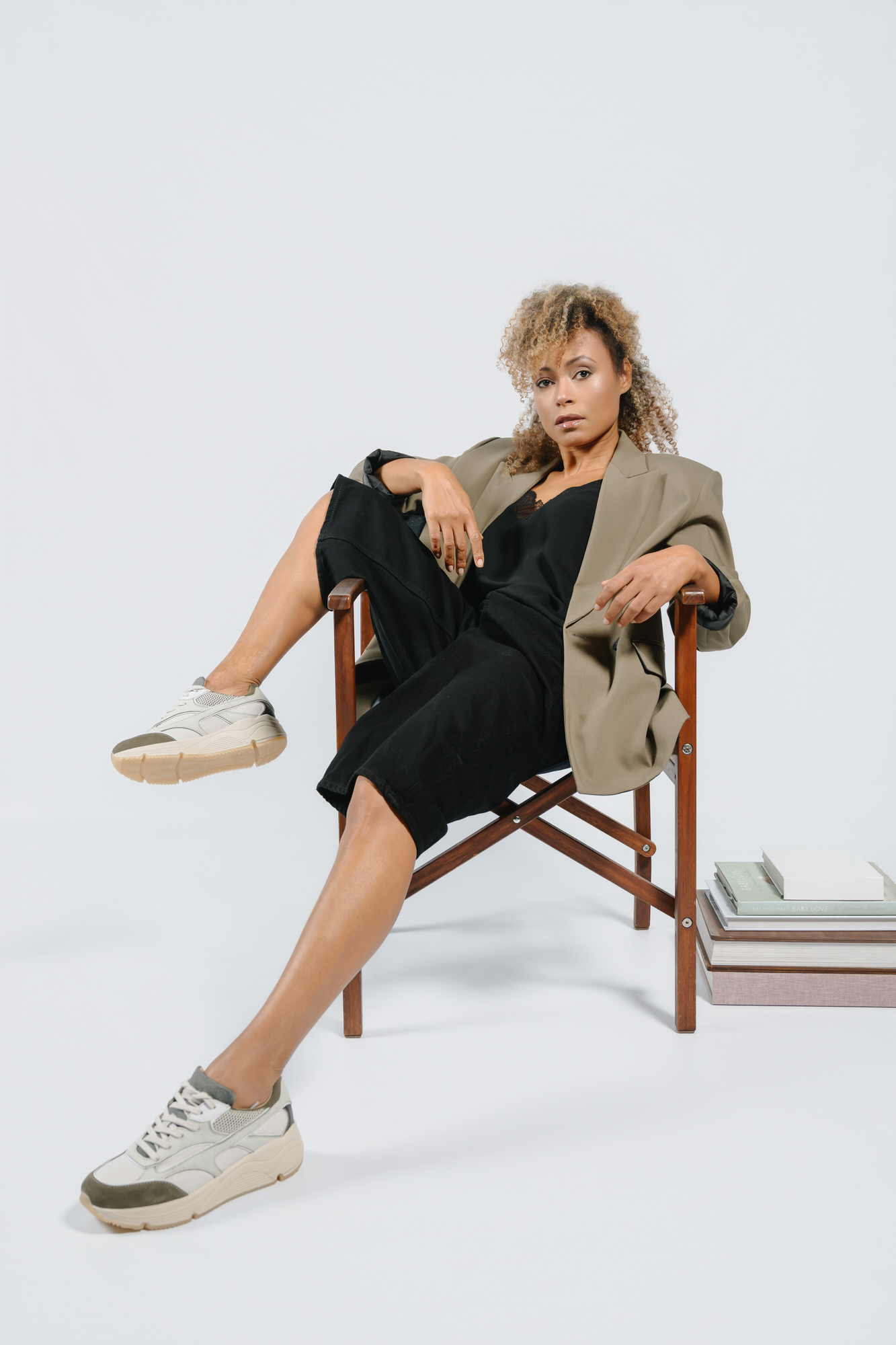 Side view of AQA chunky sneakers with thick beige soles and olive green details, showcased in a dynamic pose on a wooden chair.